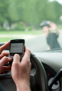 Vertical image of dangerous driving. Man texting while driving is about to hit a boy on a scooter.