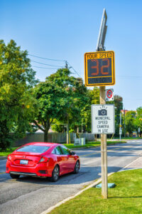 Toronto, Canada - September 12, 2024: A red vehicle drives a by speed camera in a residential district.