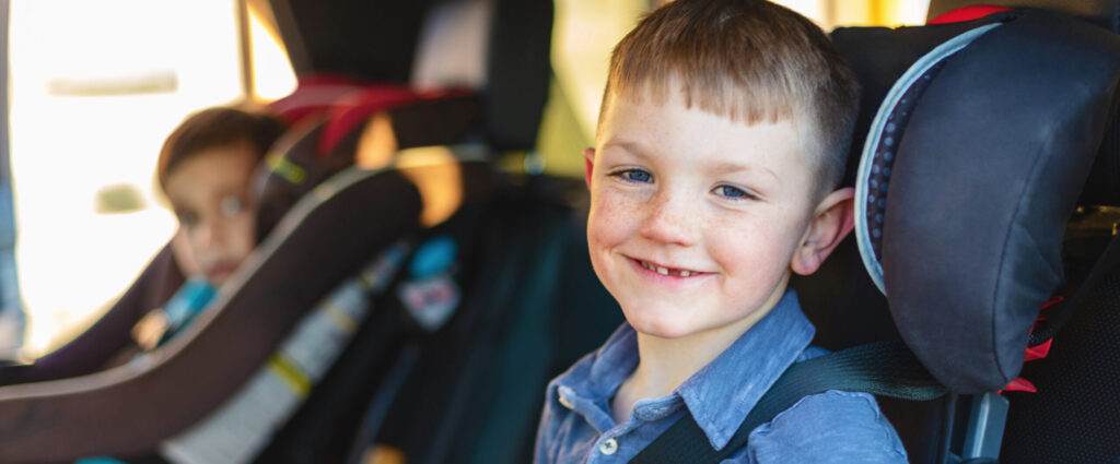 Young Two Parent Family with Mixed Race Adopted Children Showing Safe Driving Habits and Children Properly Placed in Car seats and Booster Seats and Seat Belted Young Boys in Car Seats
